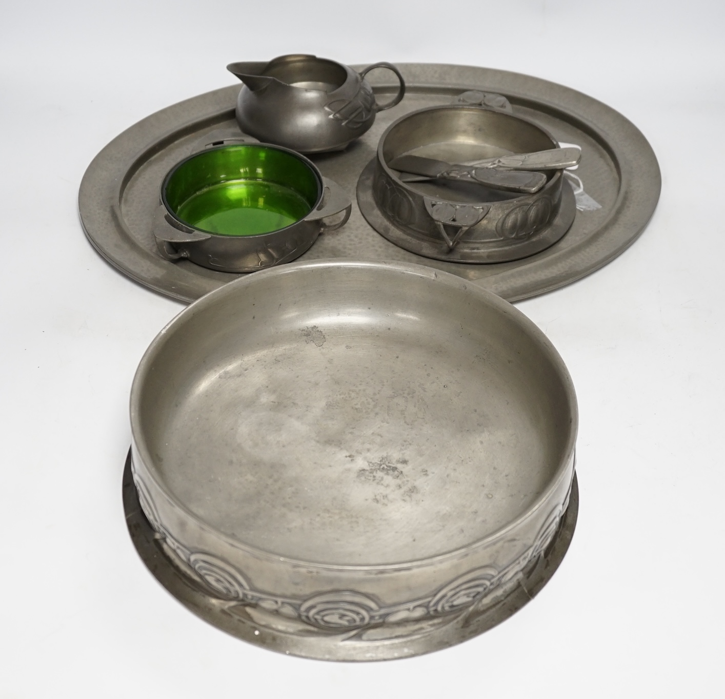 Seven items of pewter, including a Liberty Tudric tray, 45.5cm width, an Archibald Knox jug, a large Tudric bowl, 27cm diameter, a dish with glass liner, another dish and two paper knifes